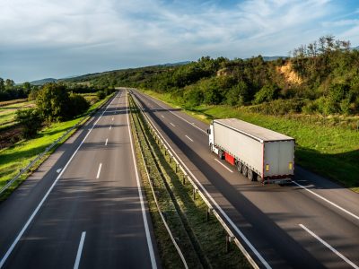 Truck,With,Semi-trailer,Driving,Along,Highway,On,The,Sunset,Background.